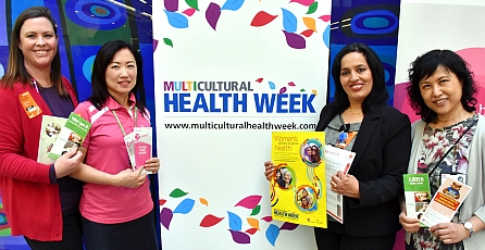 Four woman holding pamplets next to an Multicultural health week banner